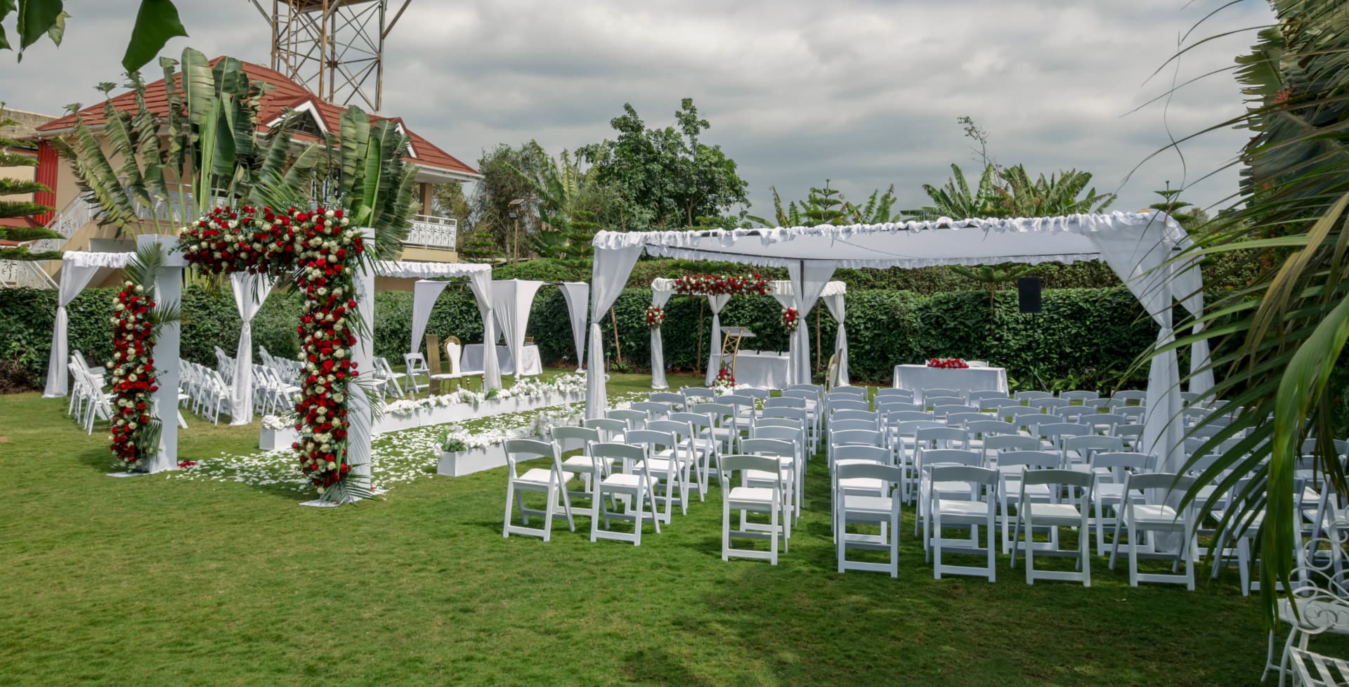 Rows of white chairs and floral arches prepared on the garden lawn