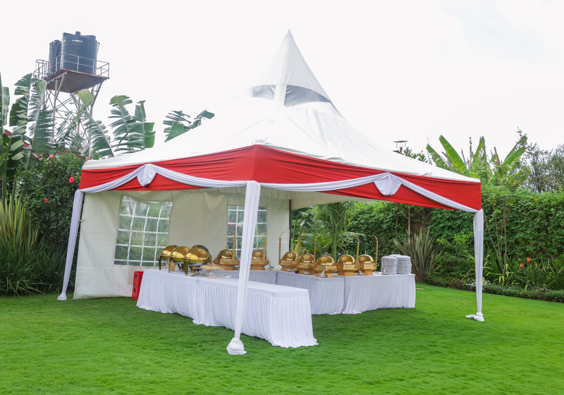 Covered outdoor buffet station with serving equipment on the garden lawn