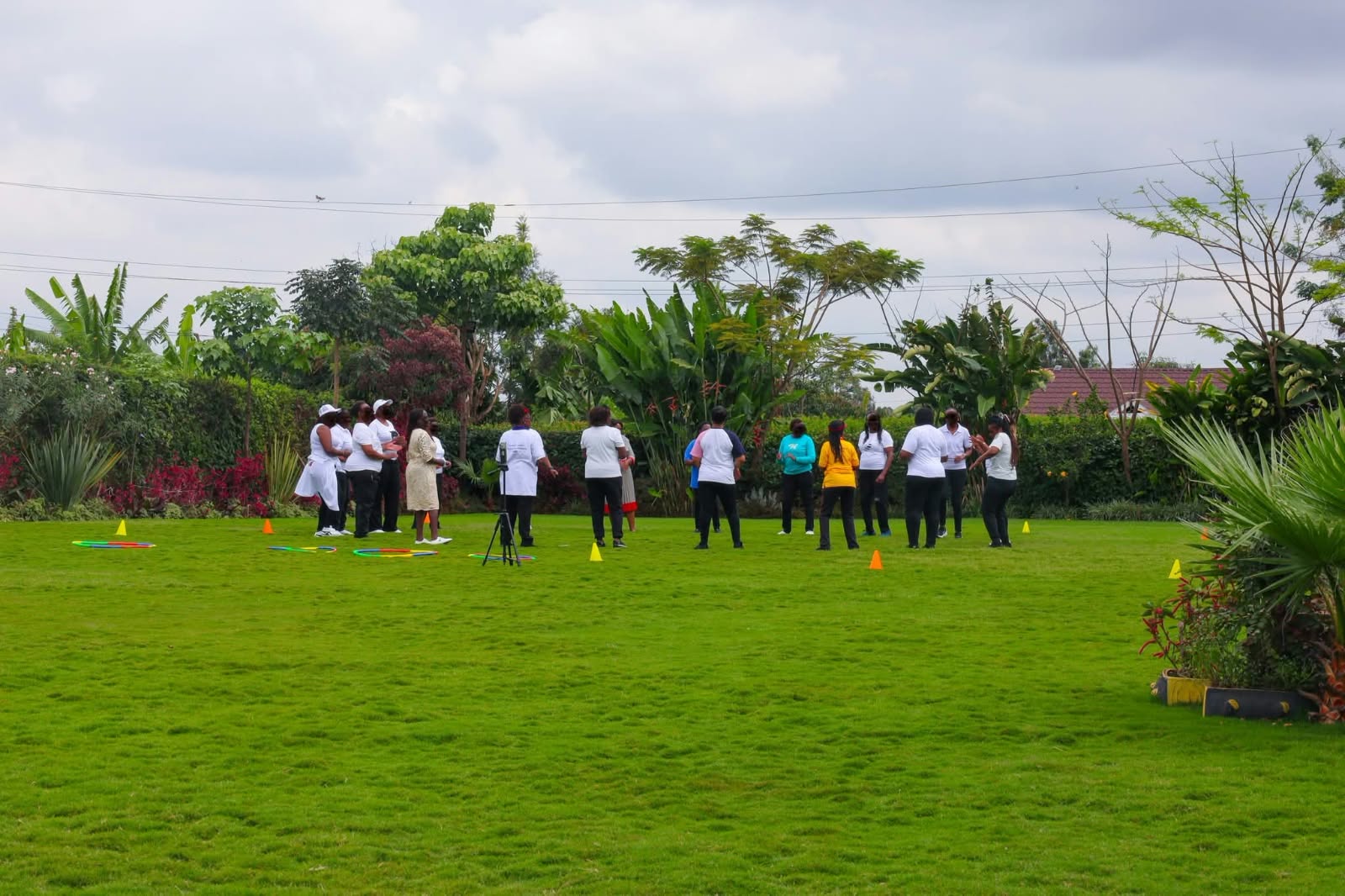 Team taking part in outdoor activities with colourful cones and hoops on the green garden lawn