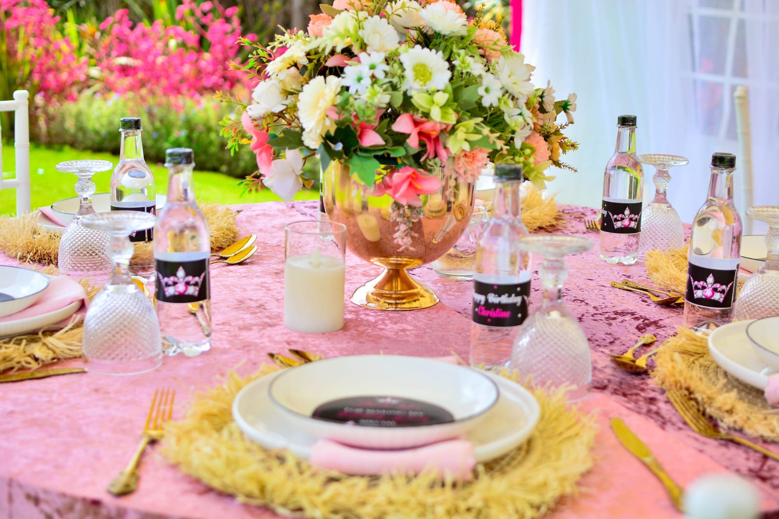 Pink velvet birthday tablescape with gold cutlery, floral centrepiece and personalised Daynight Blues bottles