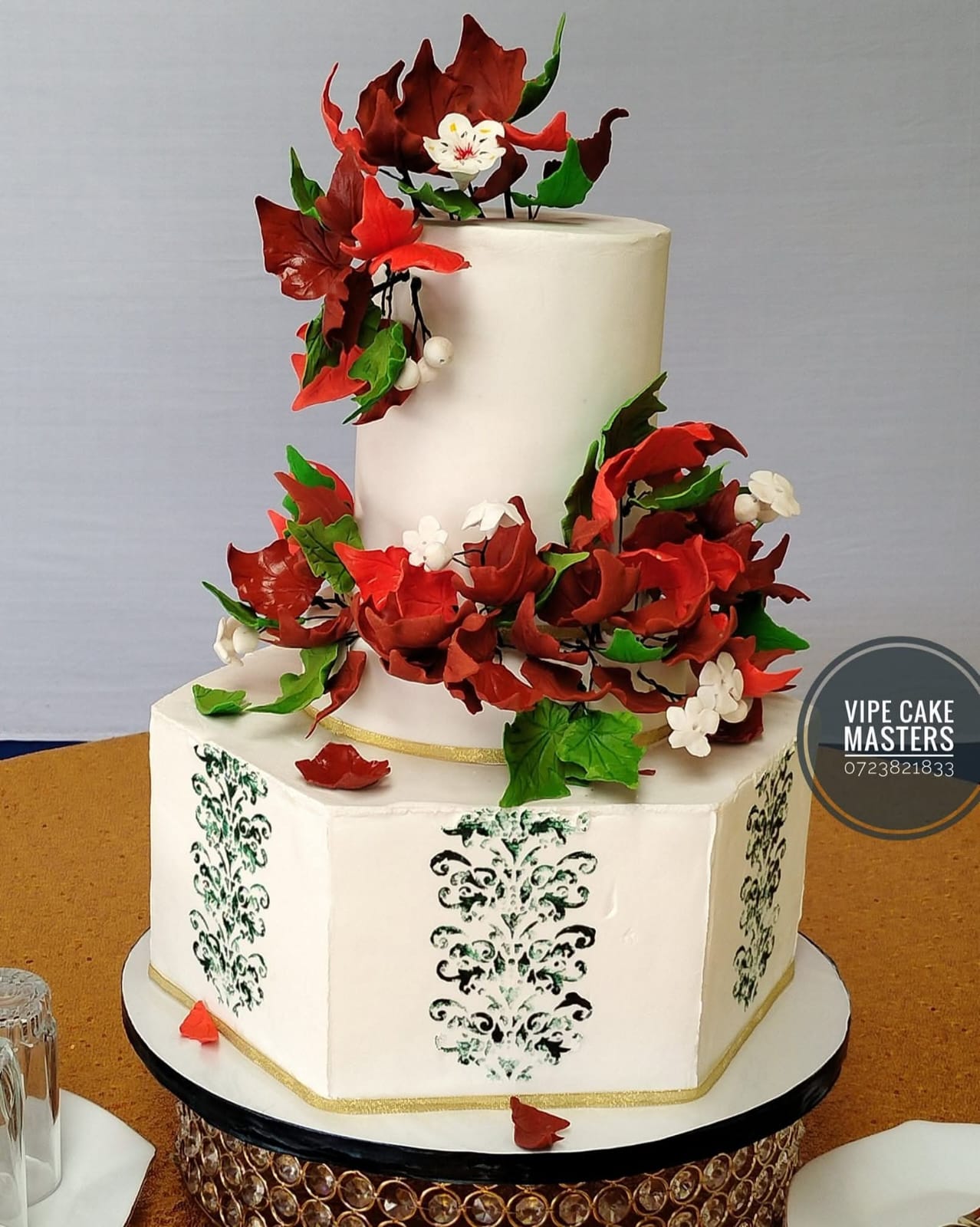 Two-tier white wedding cake with red sugar flowers by Vipe CakeMasters & Events