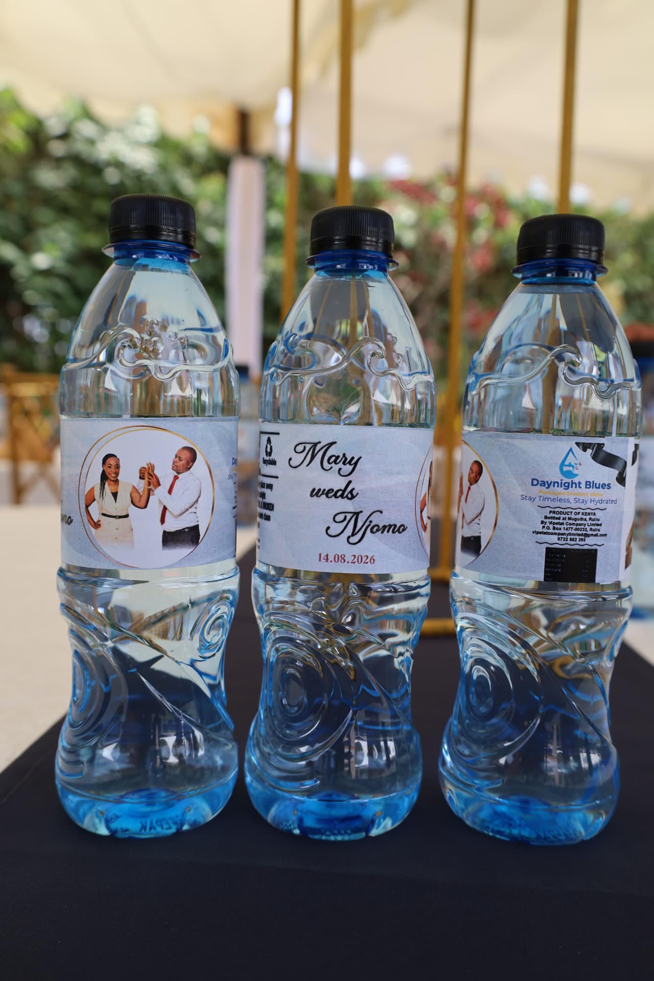 Three Daynight Blues bottles with personalised couple photo labels at a wedding