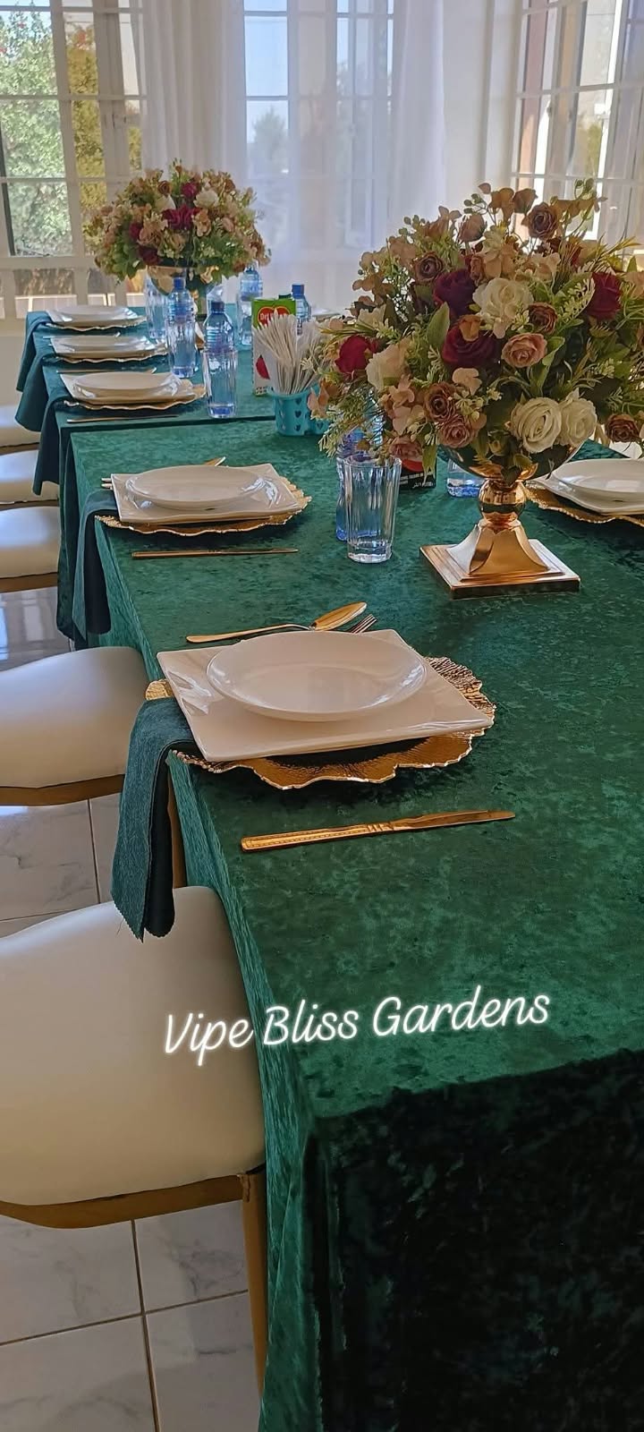 Conference table with green linen, floral centrepieces and place settings beside bright garden-facing windows